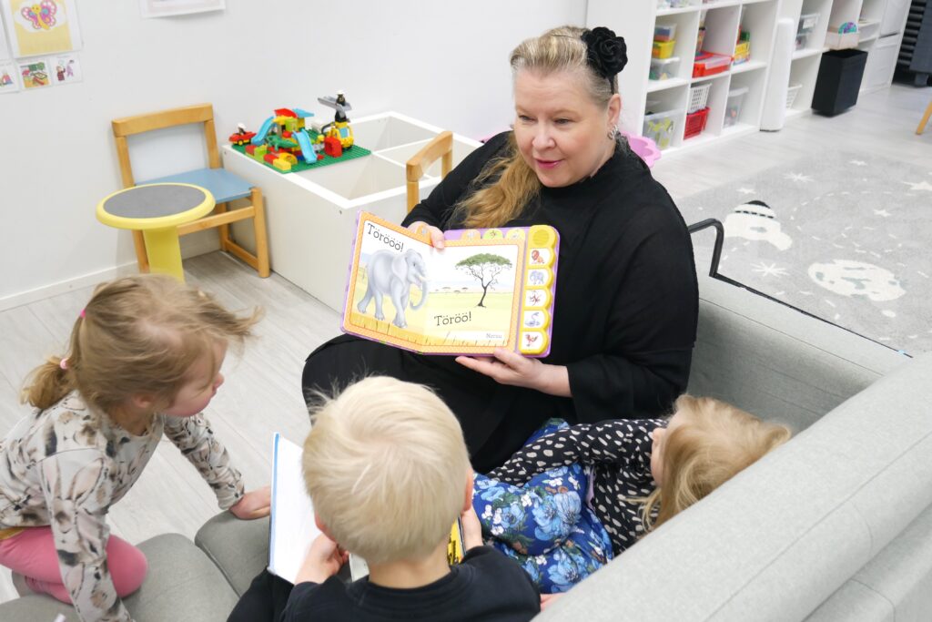 Päiväkodin työntekijä näyttää lapsille kuvakirjaa